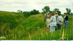 A small group of people standing next to a drainage ditch