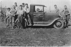 Black and white photo of several men sitting in the back of and standing by a Southeast Experiment Station truck