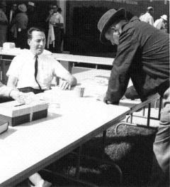 Deane Turner sitting at a table while another man fills out a form